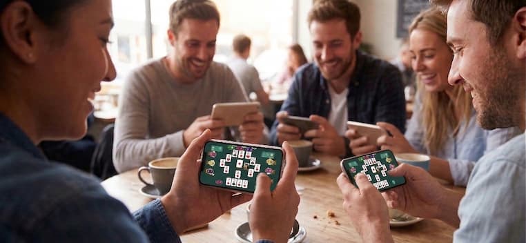 Friends playing Irish 25 card game on their phones at a cafe